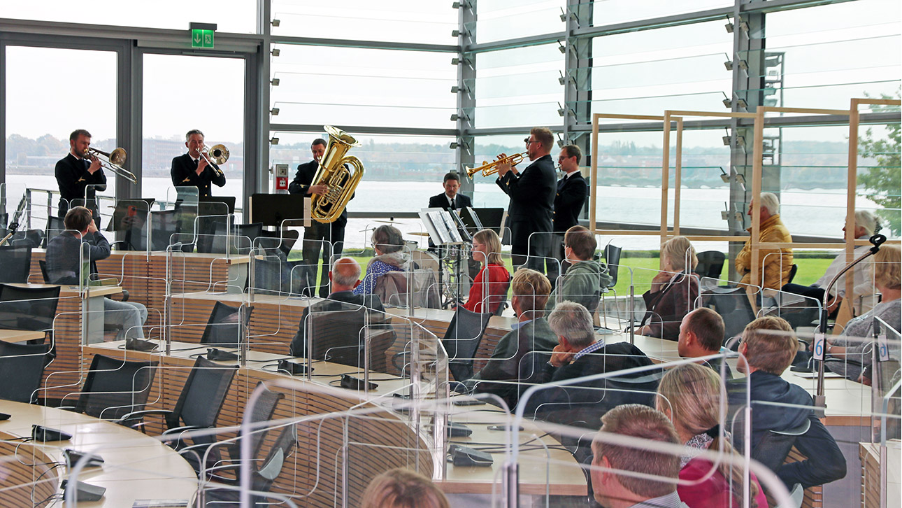 Sechs Musiker des Marinemusikkorps spielen vor sitzenden Zuschauern im Plenarsaal des Landtages.