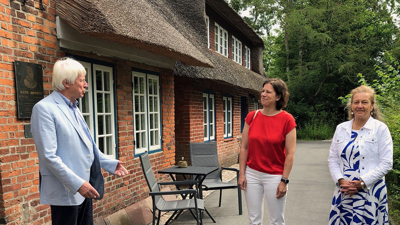 Gerd Vahder, Vorsitzender der Hans-Momsen-Gesellschaft, begrüßt Landtagspräsidentin Kristina Herbst (Mitte) und Ilse Johanna Christiansen vom Friesenrat vor dem Hans-Momsen-Haus.