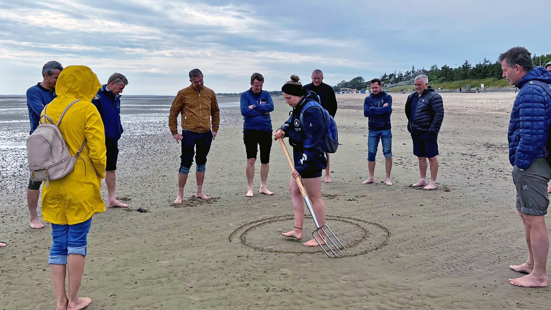Besuch Südtiroler Landtag © Foto: Landtag, Vivien Albers Die Delegation des Südtiroler Landtages steht barfüßig im Watt und hört einer Wattführerin zu, die mit einer Harke einen Kreis in den Meeresboden zieht.