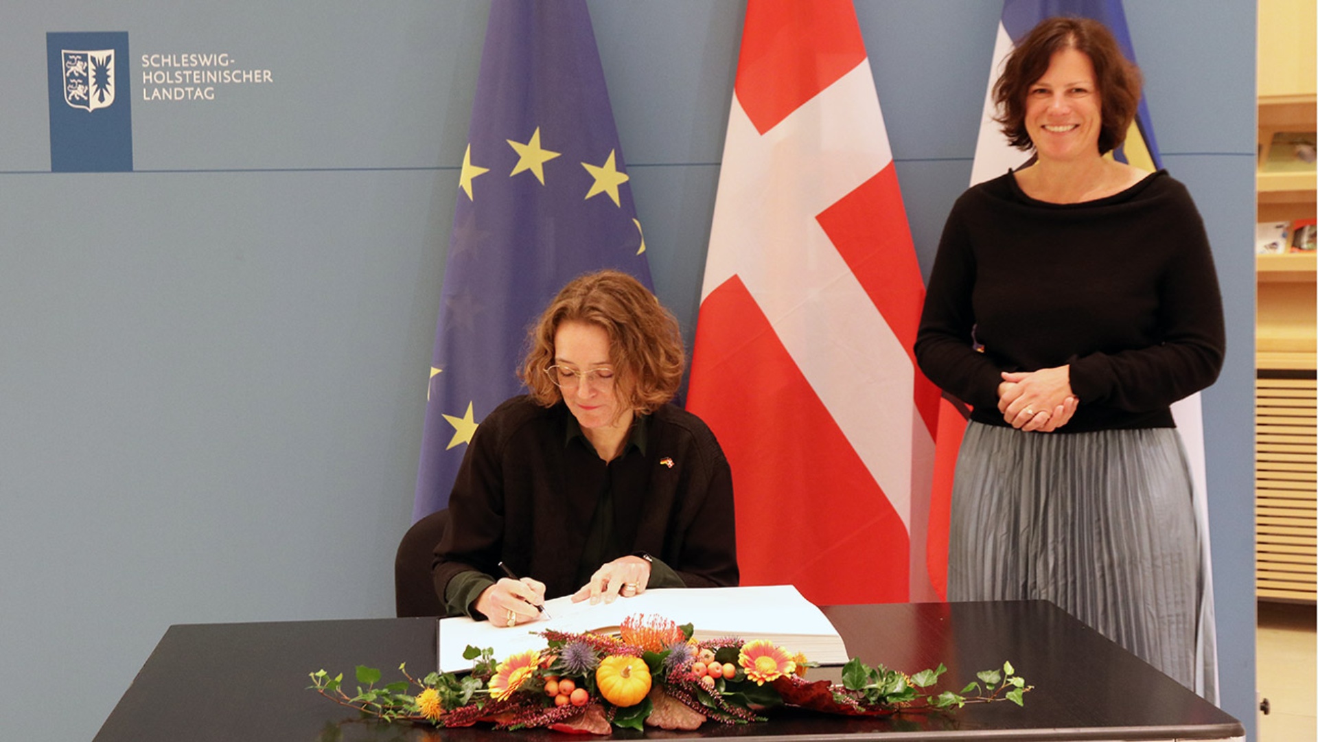 Die dänische Botschafterin Susanne Hyldelund trägt sich in das Gästebuch des Schleswig-Holsteinischen Landtages ein.