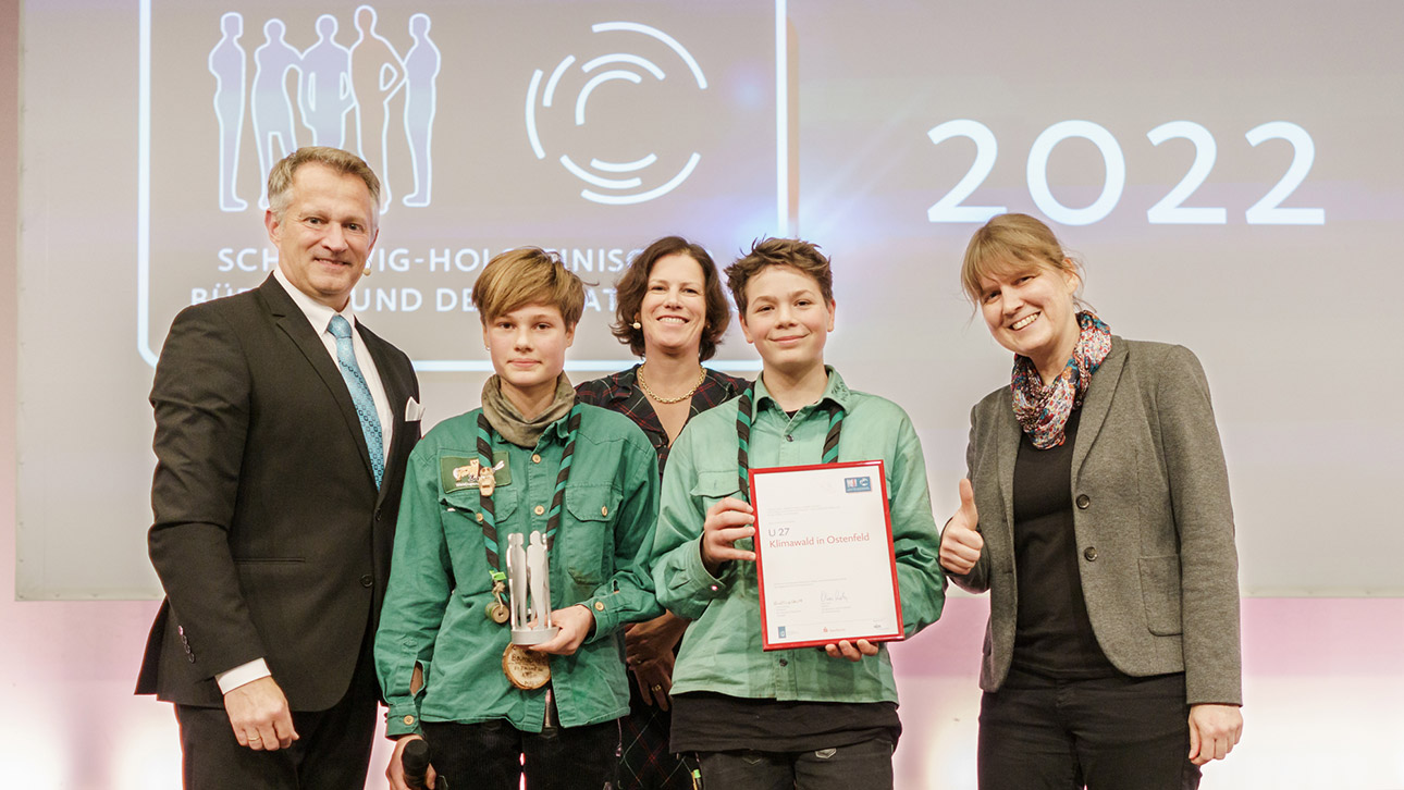 Zwei Jugendliche und eine Erwachsene der Waldjugend Nord freuen sich mit Landtagspräsidentin Kristina Herbst und Sparkassenchef Oliver Stolz über den zuvor übergebenen Preis.