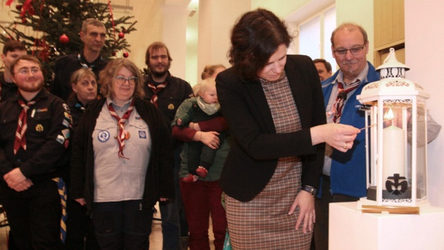 Landtagspräsidentin Kristina Herbst entzündet das Friedenslicht. Im Hintergrund: Pfadfinder