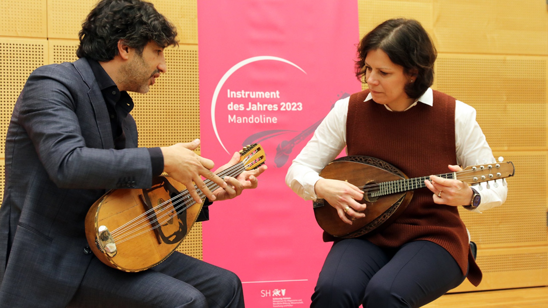 Landtagspräsident Kristina Herbst übt sich an dem "Instrument des Jahres", der Mandoline. Der renommierte israelische Musiker Avi Avital leitet sie an.