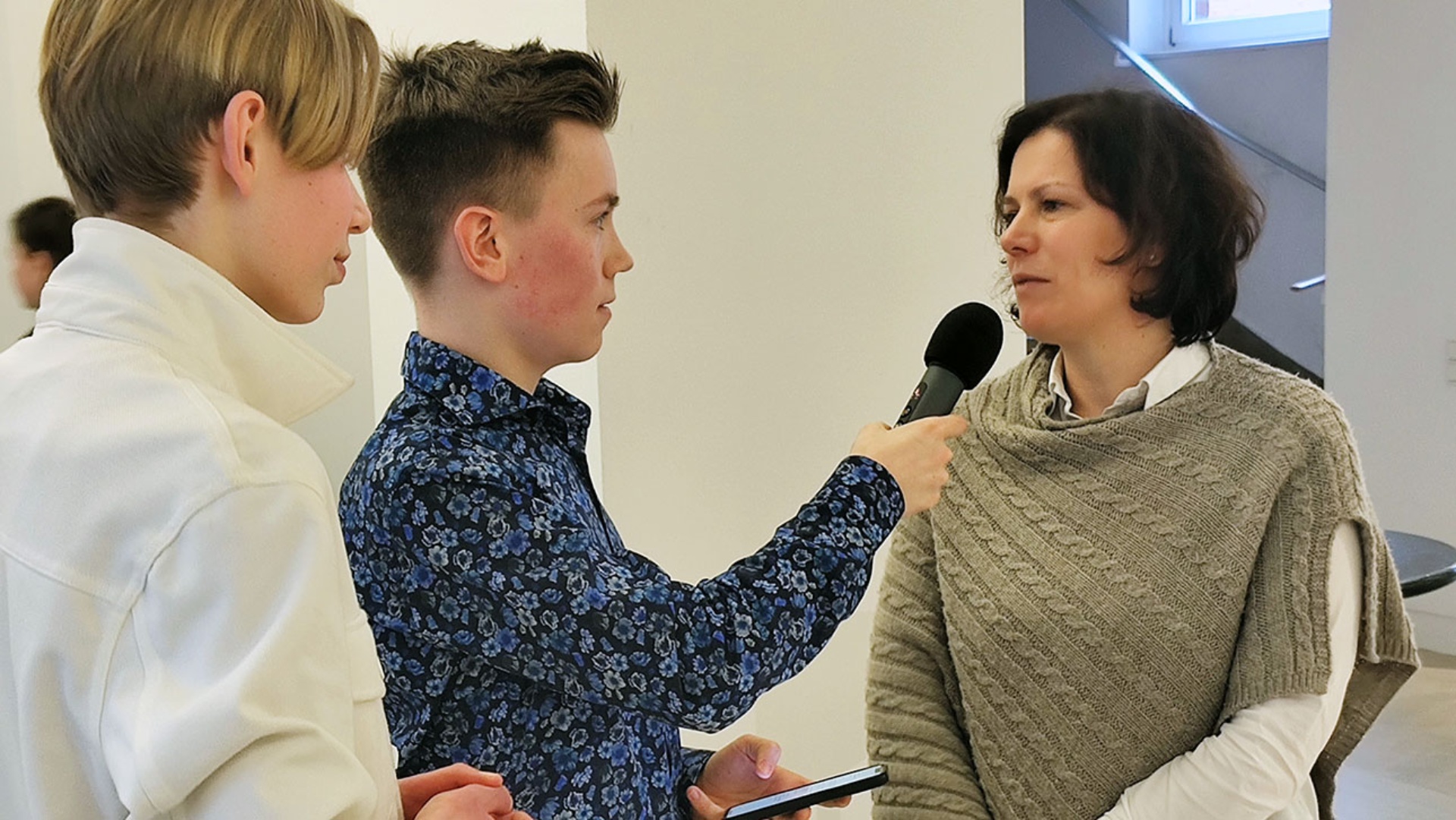 Landtagspräsidentin Kristina Herbst im Gespräch mit zwei Nachwuchsjournalisten mit Mikrofon