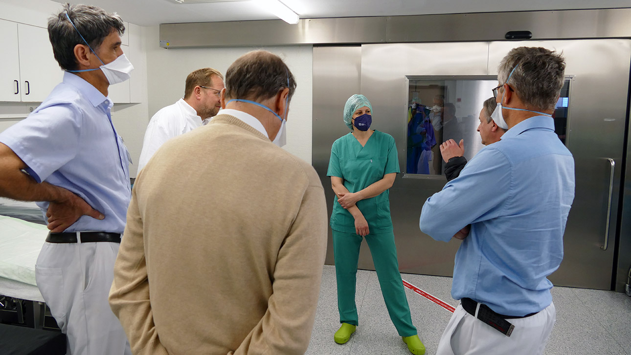  Landtagspräsidentin Kristina Herbst unterhält sich in grüner Steril-Kleidung mit Ärzten im OP-Bereich des Klinikums.
