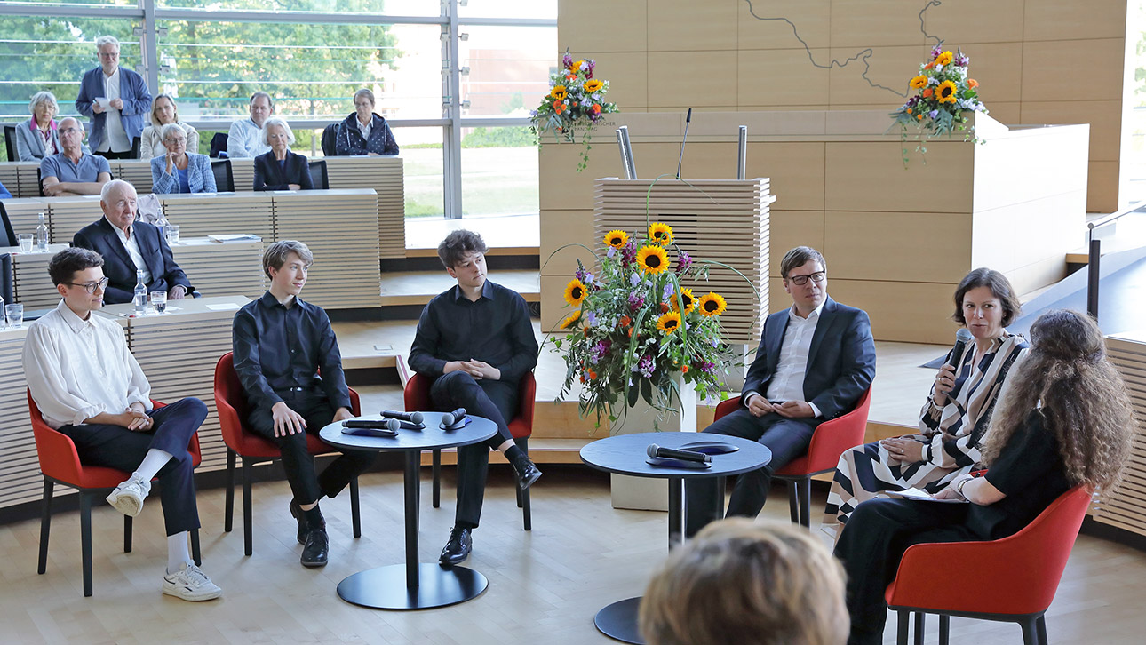 Diskussionsrunde im Plenarsaal: Landtagspräsdentin Kristina Herbst (2.v.r.)  im Gespräch mit Christian Meyer-Heidemann, Landesbeauftragter für politische Bildung (3.v.r.), Poetry-Slammer Benjamin Poliak (r.) und Mitgliedern der Jungen Camerata Academica St. Llorenc