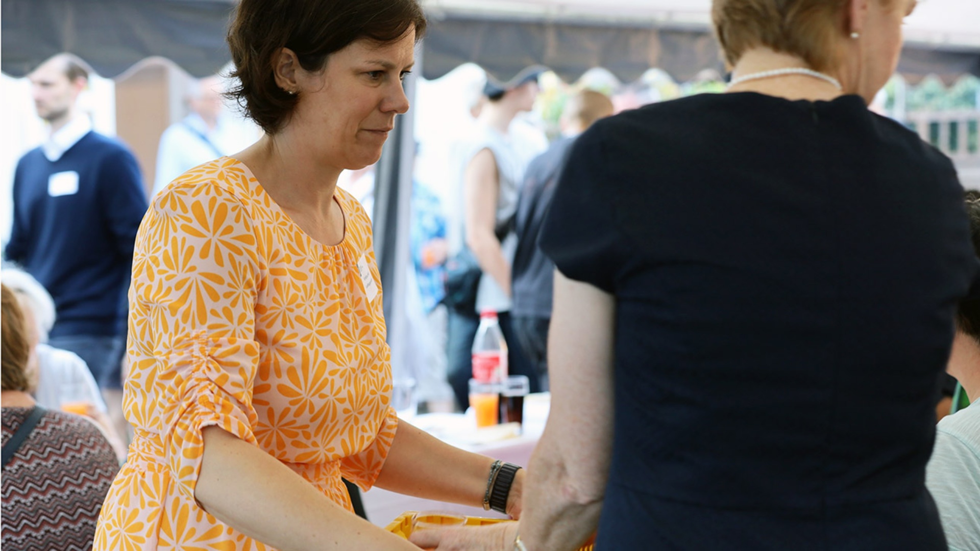 Kristina Herbst und Anette Röttger, Mitglied im Sozialausschuss, servieren Gästen das Essen auf der Terrasse des Sophie-Kunert-Hauses