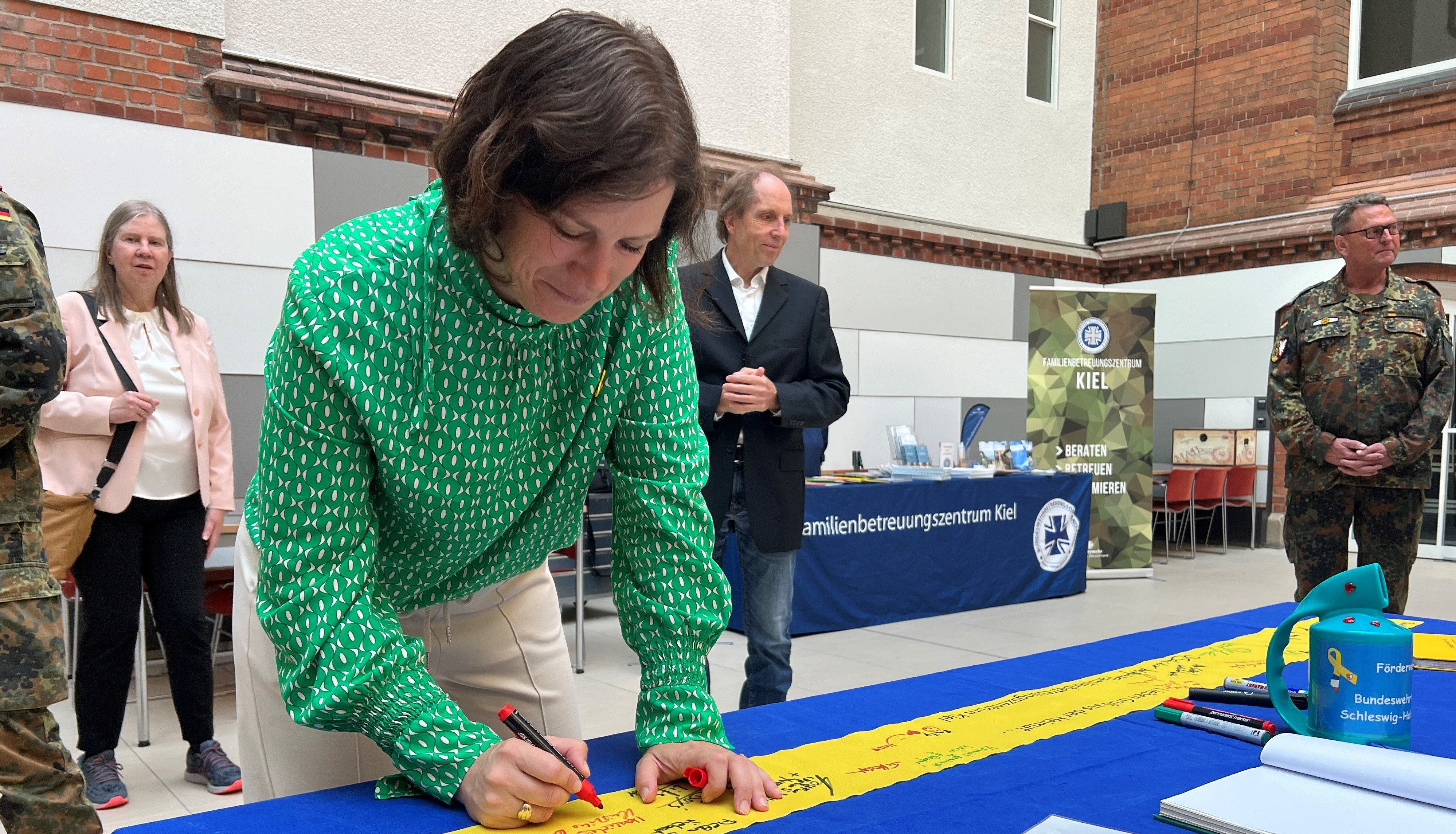 Landtagspräsidentin Kristina Herbst unterschreibt auf dem „Gelben Band der Verbundenheit“.