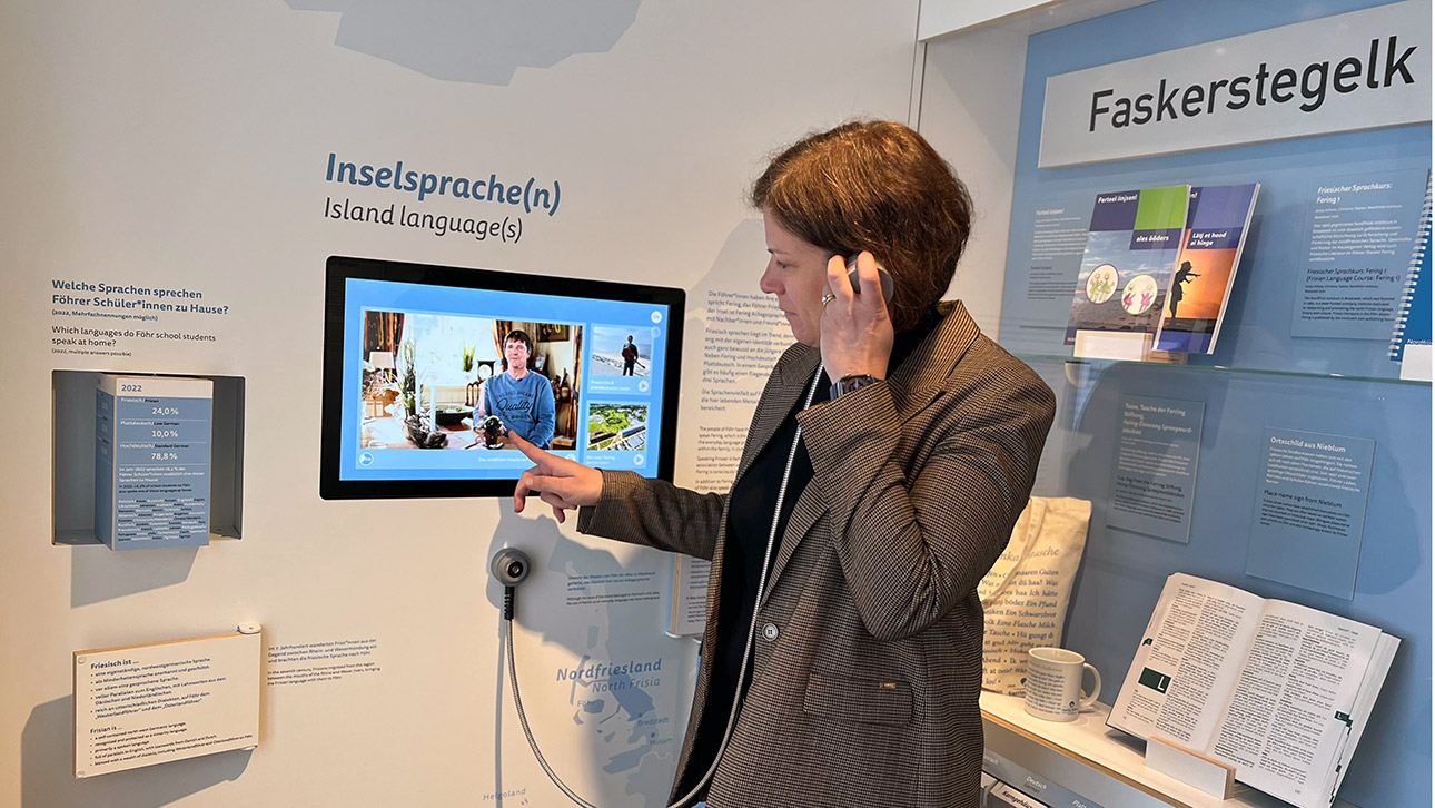 Interaktiv übt Landtagspräsidentin Herbst mit einem Ohrhörer die friesische Sprache im Dr.-Carl-Häberlin-Friesen-Museum