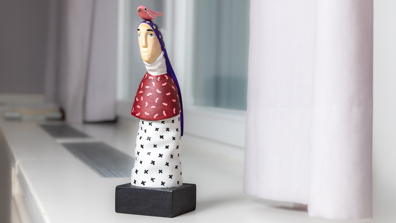 Eine Figur, die eine Frau mit einem Vogel auf dem Kopf zeigt.