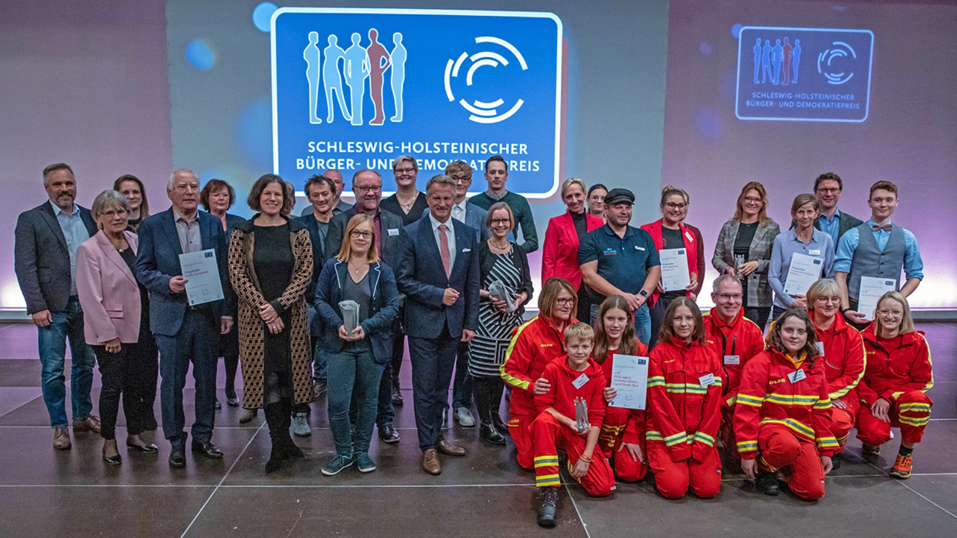 Die Gewinner und Nominierten des 20. Bürger- und Demokratiepreises stehen auf der Bühne in der Büdelsdorfer Thormannhalle. 