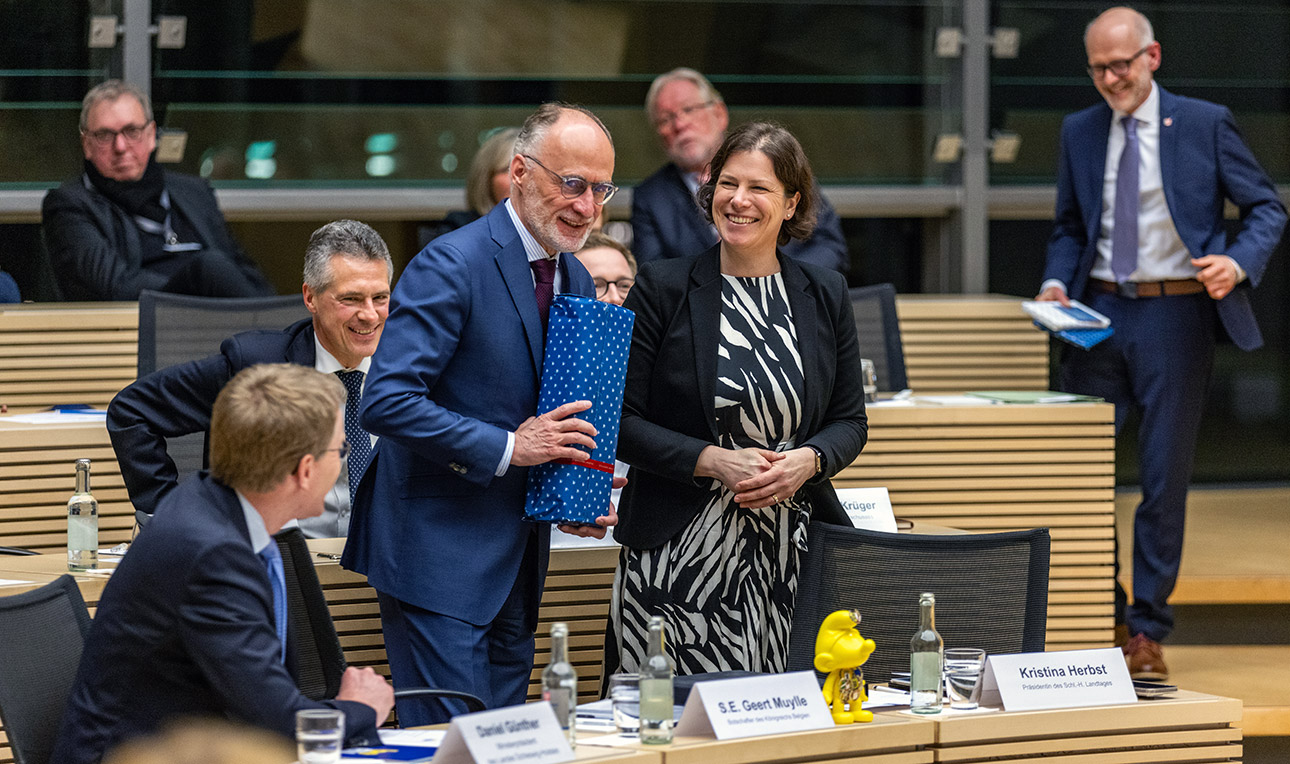 Landtgapräsidentin Kristina Herbst überreicht dem belgischen Botschafter Geert Muylle anlässlich des Länderabends Belgien im Plenarsaal des Landtages ein Gastgeschenk – eine Flasche Himbeergeist.