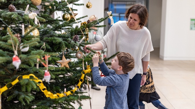 Ein Kind der Kita Hoppetosse schmückt den Weihnachtsbaum im Foyer des Landeshauses