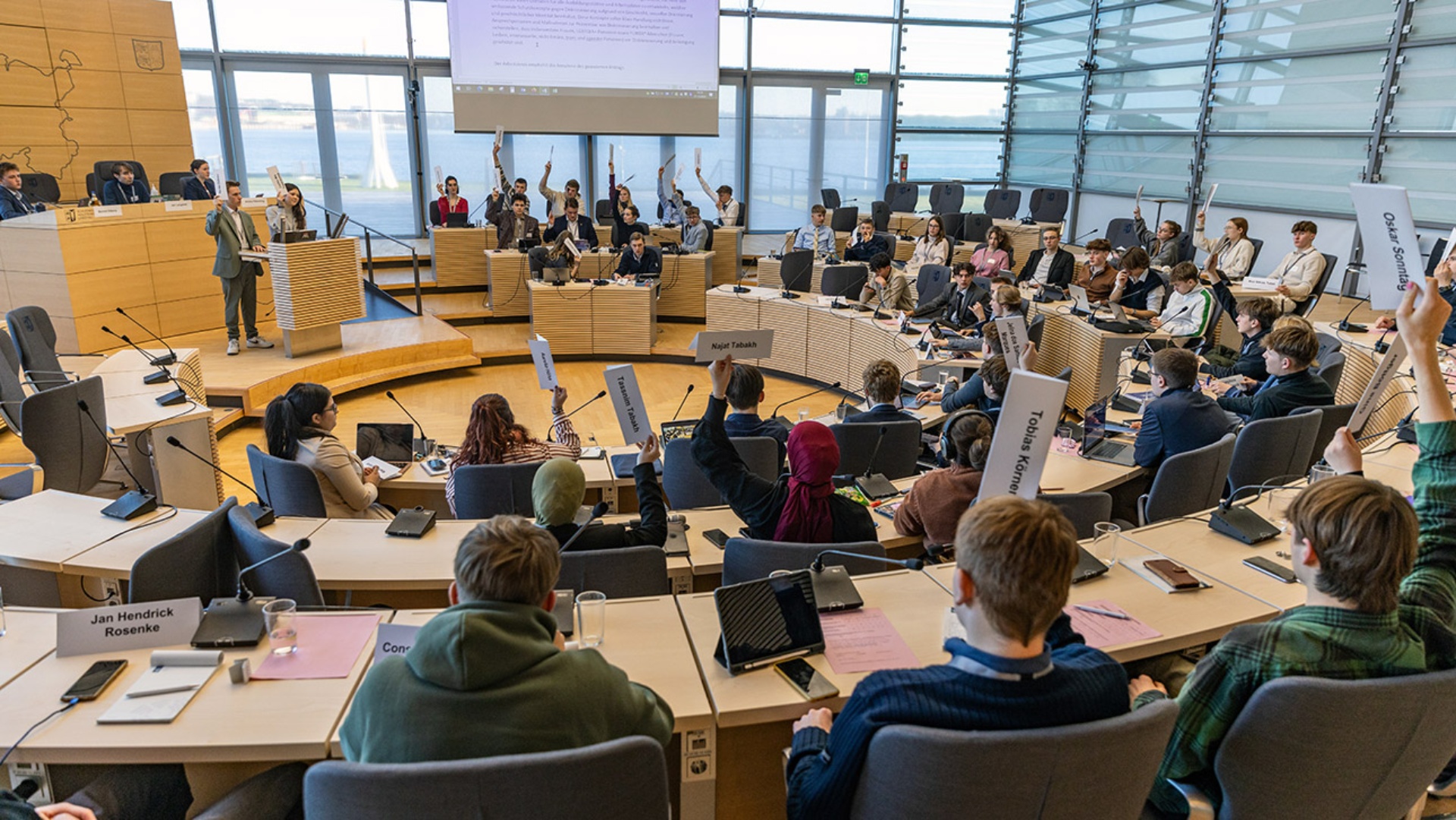 Jugendliche  stimmen mit hochgehaltenen Stimmzetteln über einen Antrag im Plenarsaal des Schleswig-Holsteinischen Landtages ab.