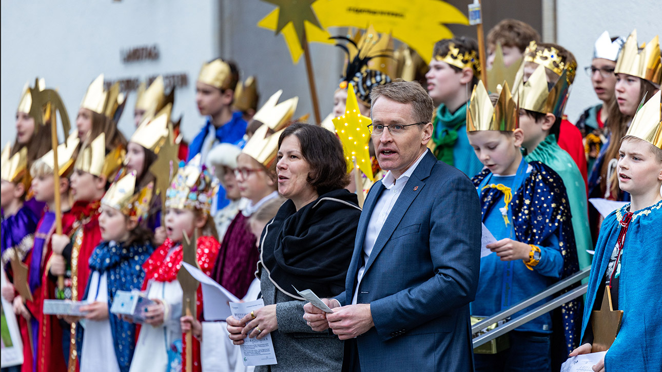Mit Parlamentspräsidentin Kristina Herbst und Ministerpräsident Daniel Günther singen die bunt gekleideten Sternsinger vor dem Landeshaus ein erstes Lied.