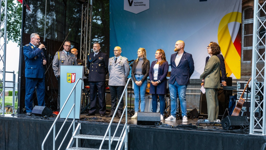 Gesprächsrunde auf einer Bühne, unter anderem mit Oberst Skamel, Kommandeur des Landeskommandos Schleswig-Holstein und Landtagspräsidentin Kristina Herbst.