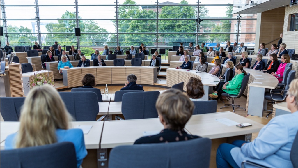 Blick in den Plenarsaal, wo auf den Abgeordnetenplätzen zahlreiche Mandatsträgerinnen sitzen.
