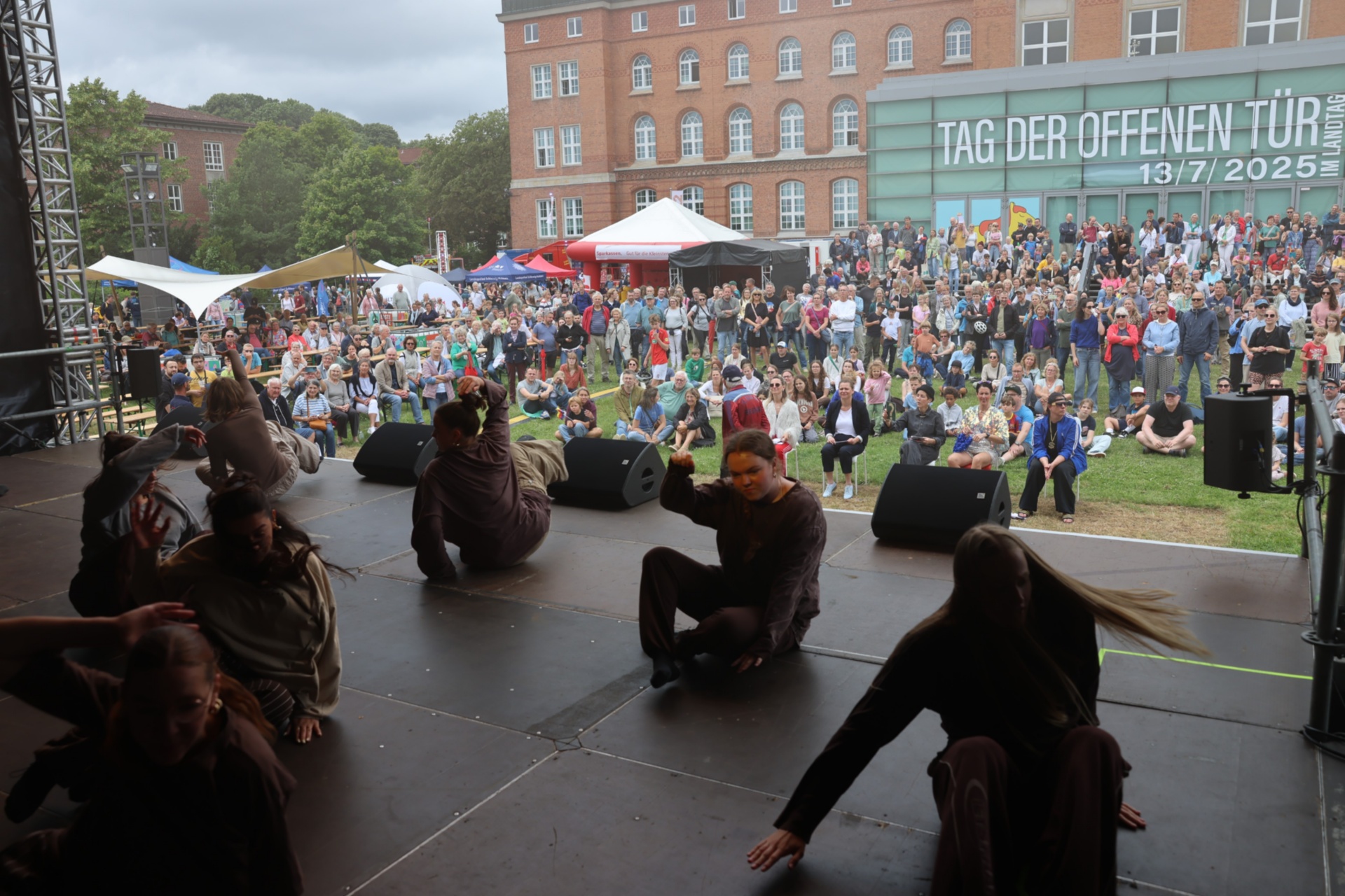Tänzer sind auf der Bühne und im Hintergrund sind die Besucherinnen und Besucher des Tages der offenen Tür vorm Plenarsaal zu sehen. 
