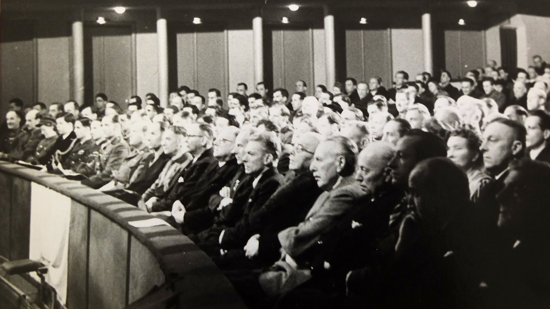 Eröffnung des ersten ernannten Landtages, 26. Februar 1946: Das Parkett des Stadttheaters. Im Vordergrund die Abgeordneten, im Hintergrund britische Militärangehörige.