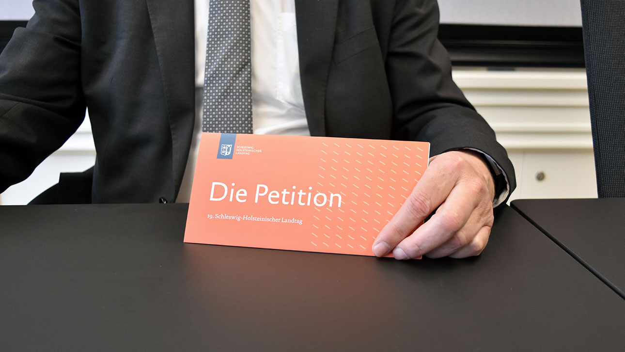 Ein orangefarbenes Schild mit der Aufschrift Petition lädt zum Workshop des Petitionsausschusses am Tag der offenen Tür ein