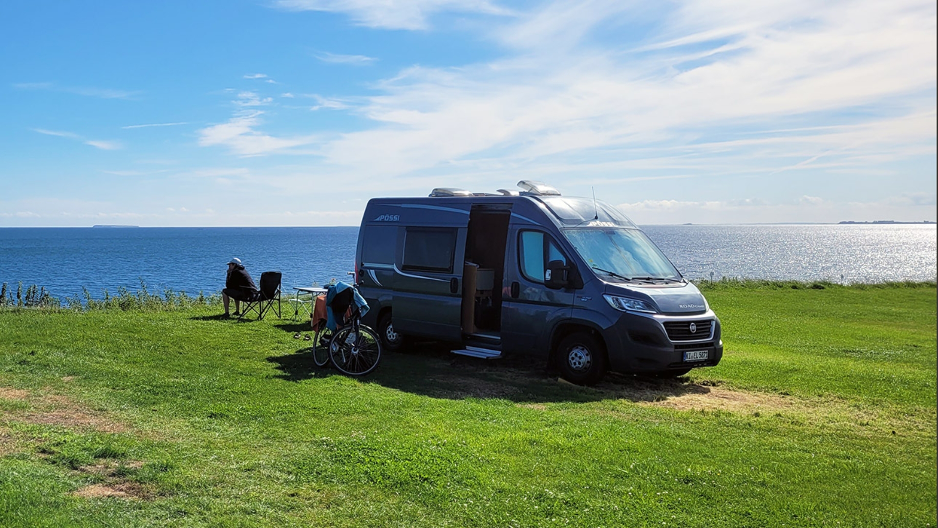 Ein Wohnmobil steht auf einer Wiese am Meer 