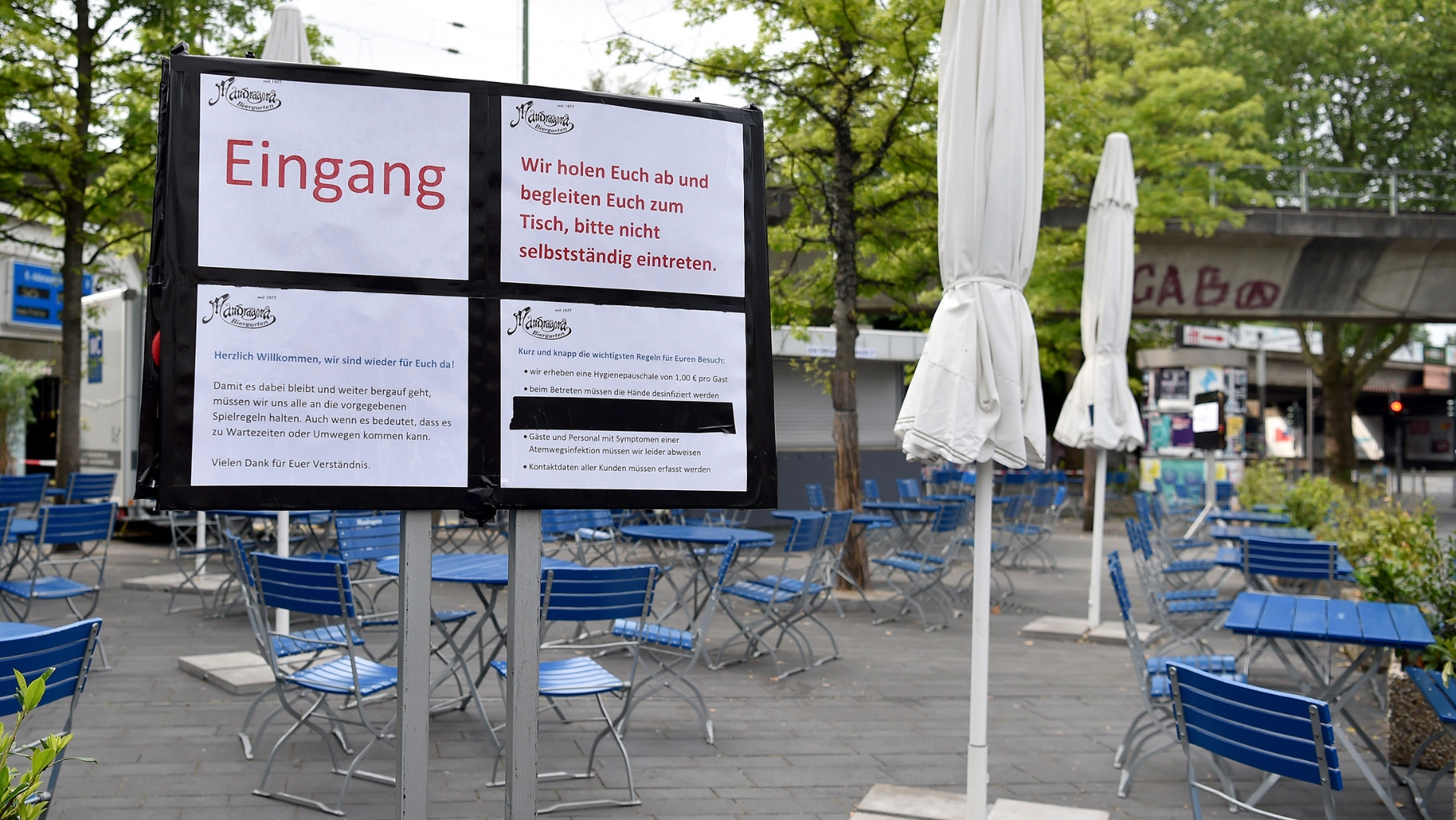 Ein Schild erklärt den Gästen das Verhalten während der Corona-Beschränkungen in einem Biergarten.