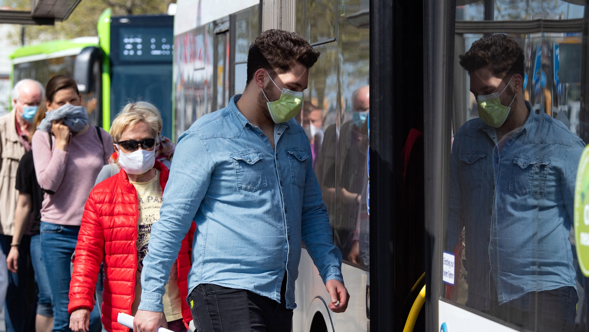 Fahrgäste mit Mundschutz steigen in einen Bus ein.
