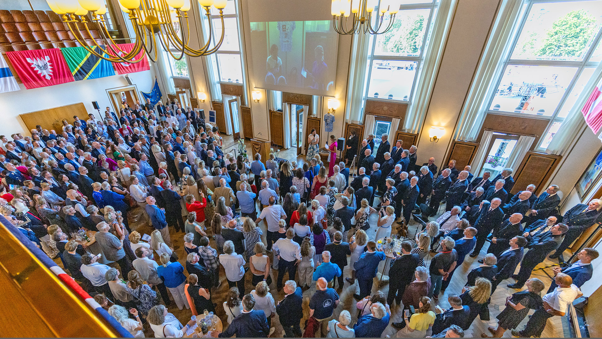 Im Kieler Rathaus stehen hunderte Personen zusammen und hören Landtagspräsidentin Kristina Herbst zu, die mit einem Mikrofon an einem Podium steht.