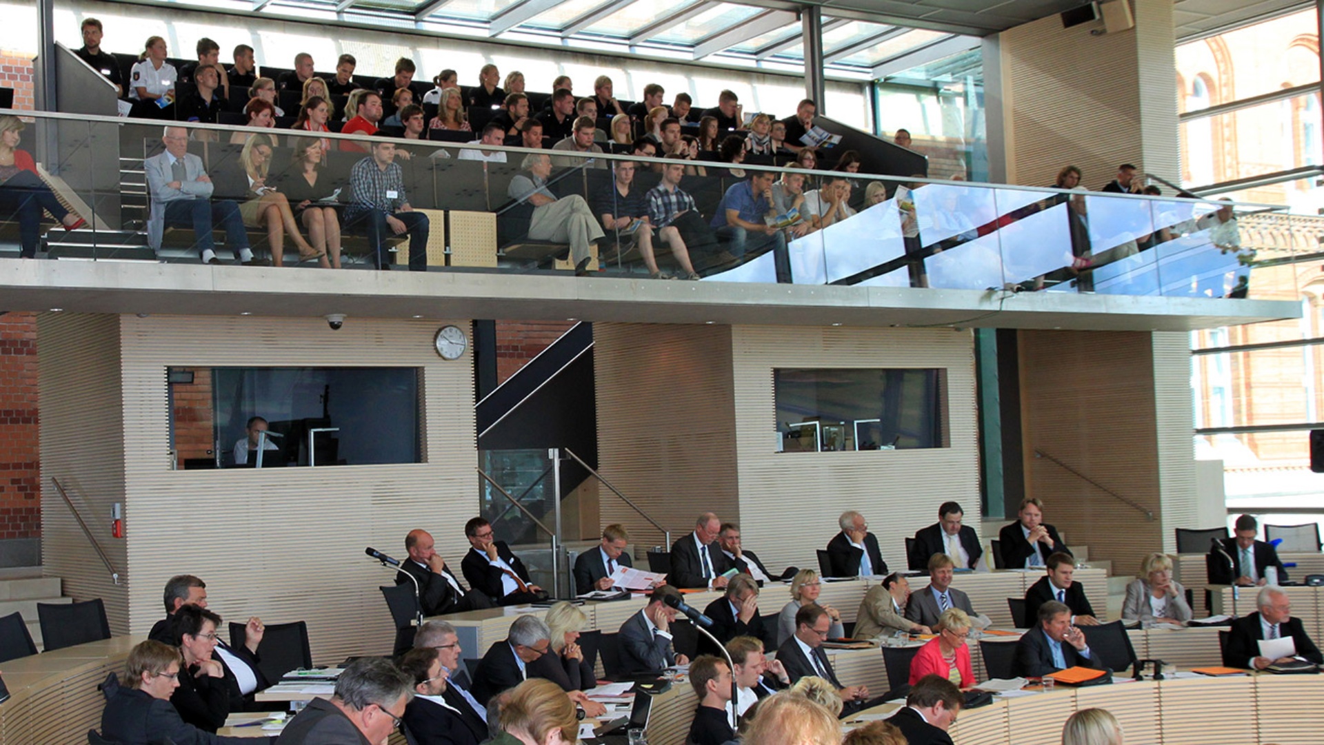 Besucher schauen sich eine Plenarsitzung von der Besuchertribüne aus an.