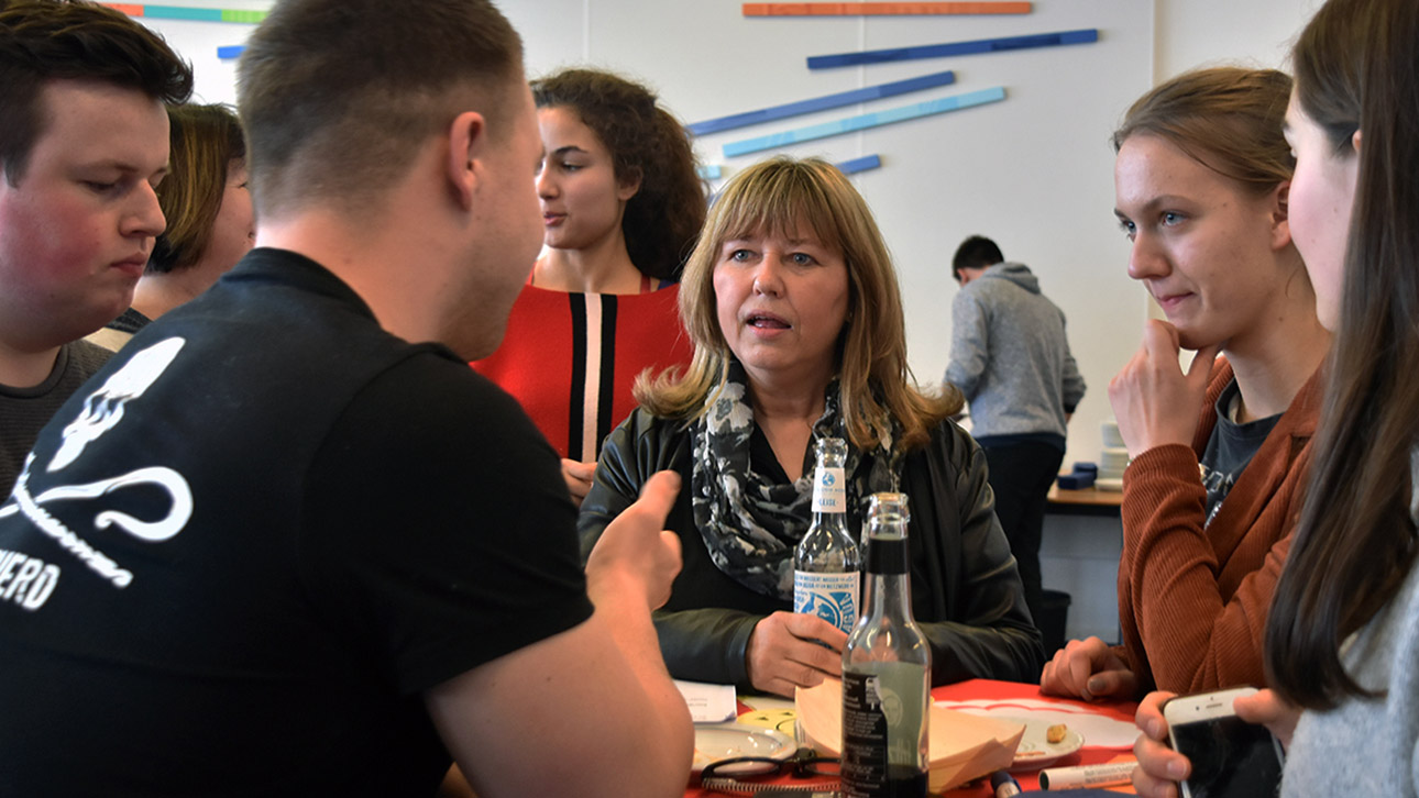 Die SPD-Abgeordnete Sandra Redmann diskutiert mit Jugendlichen an einem Stehtisch im Kasino des Landtages.