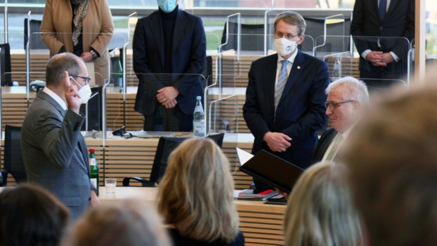 Christoph Brüning spricht vor Landtagspräsident Schlie den Amtseid. Ministerpräsident Günther schaut zu.