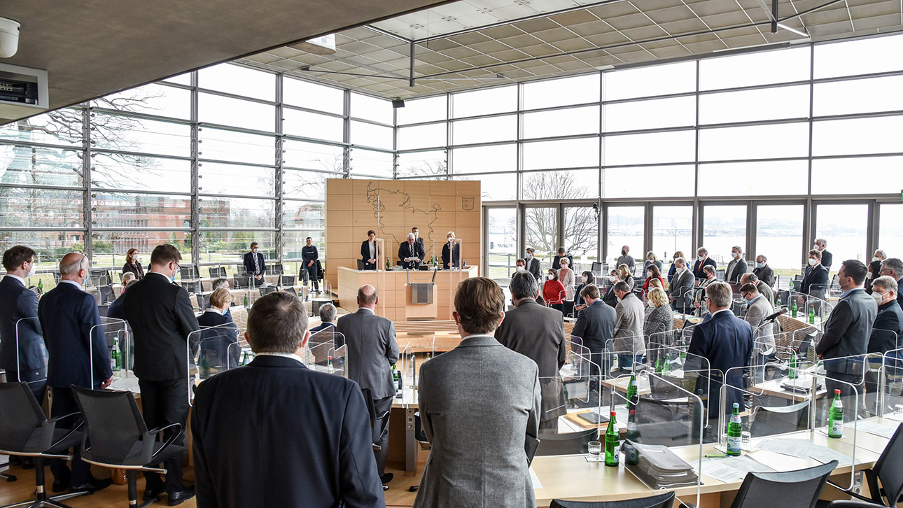 Stehend gedenken die Abgeordneten der Toten der Corona-Pandemie