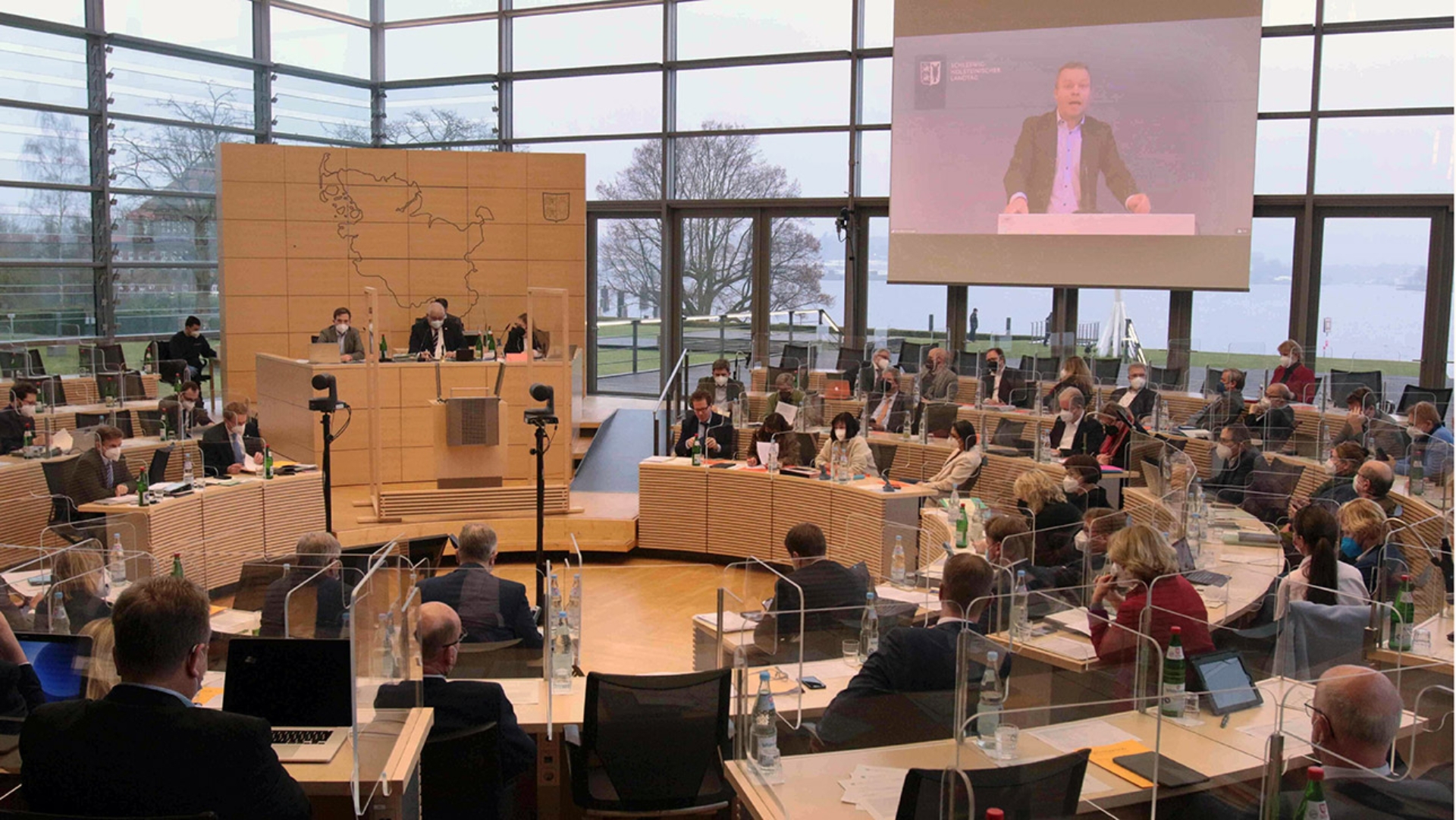 Der parteilose Abgeordnete Frank Brodehl ist aus einem Ausschussraum im Landtag auf einer Videowand im Plenarsaal zugeschaltet.