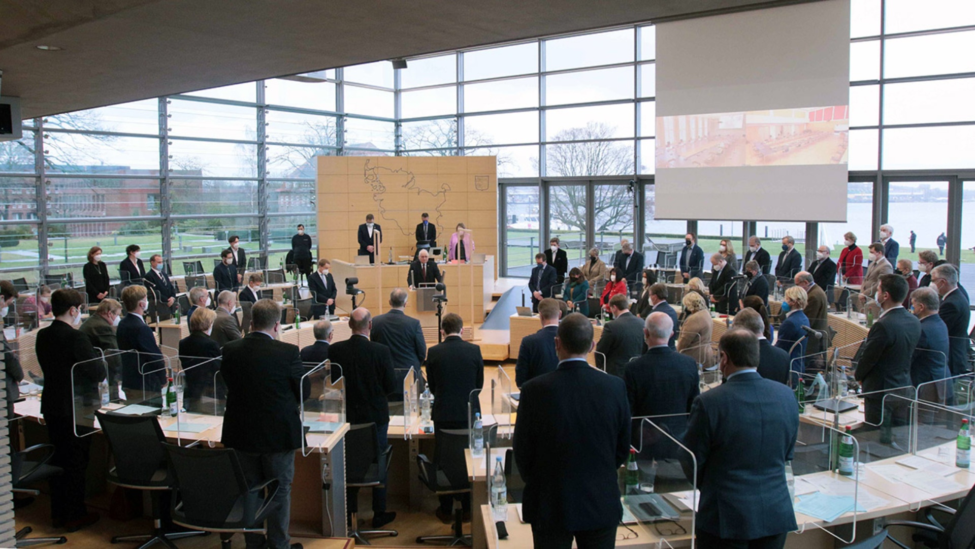 Stehend gedenken die Abgeordneten im Plenarsaal in einer Gedenkminuten der Opfer der NS-Herrschaft.