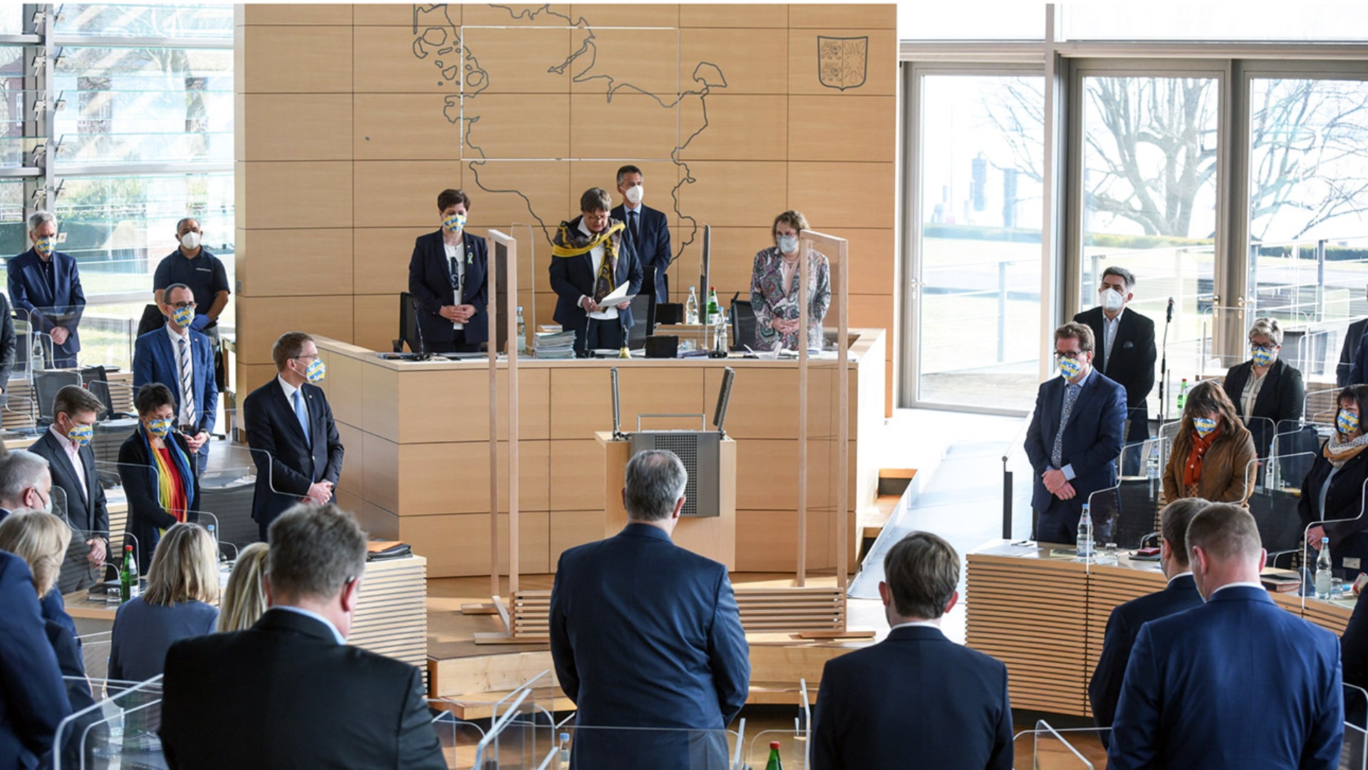 Die Abgeordneten gedenken stehend der Opfern des Ukraine-Krieges im Plenarsaal des Landtages.