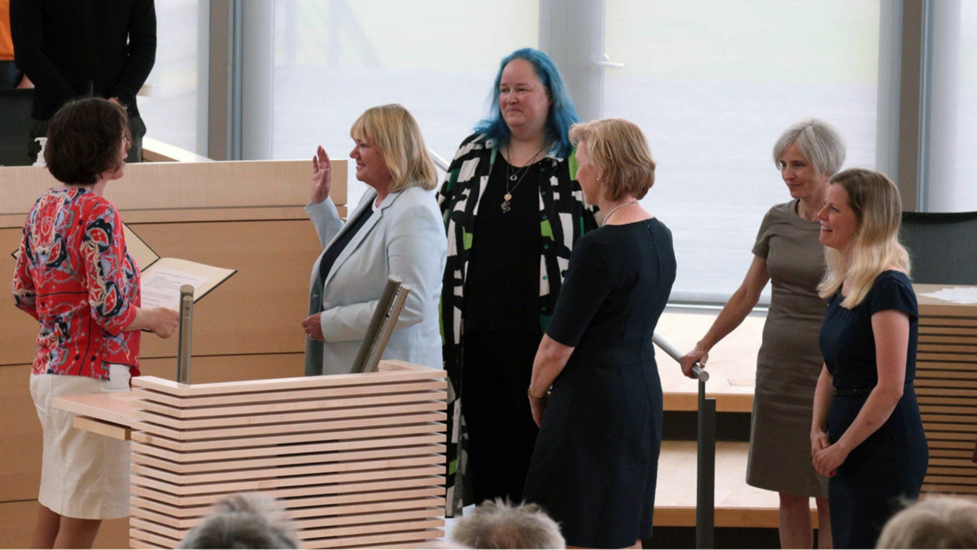 Landtagspräsidentin Kristina Herbst liest den fünf neuen Abgeordneten die Eidesformel vor. Sie stehen vor dem Podest des Landtagspräsidiums im Plenarsaal. 