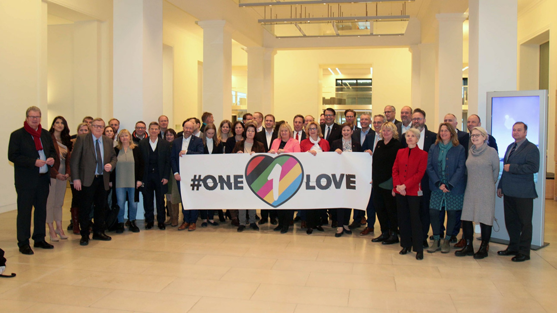 Rund 50 Landtagsabgeordnete stehen in der Eingangshalle des Landeshauses hinter einem riesigen "One-Love"-Banner 
