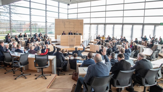 Abgeordnete im Plenarsaal des Schleswig-Holsteinischen Landtages heben bei Abstimmung ihre Arme.