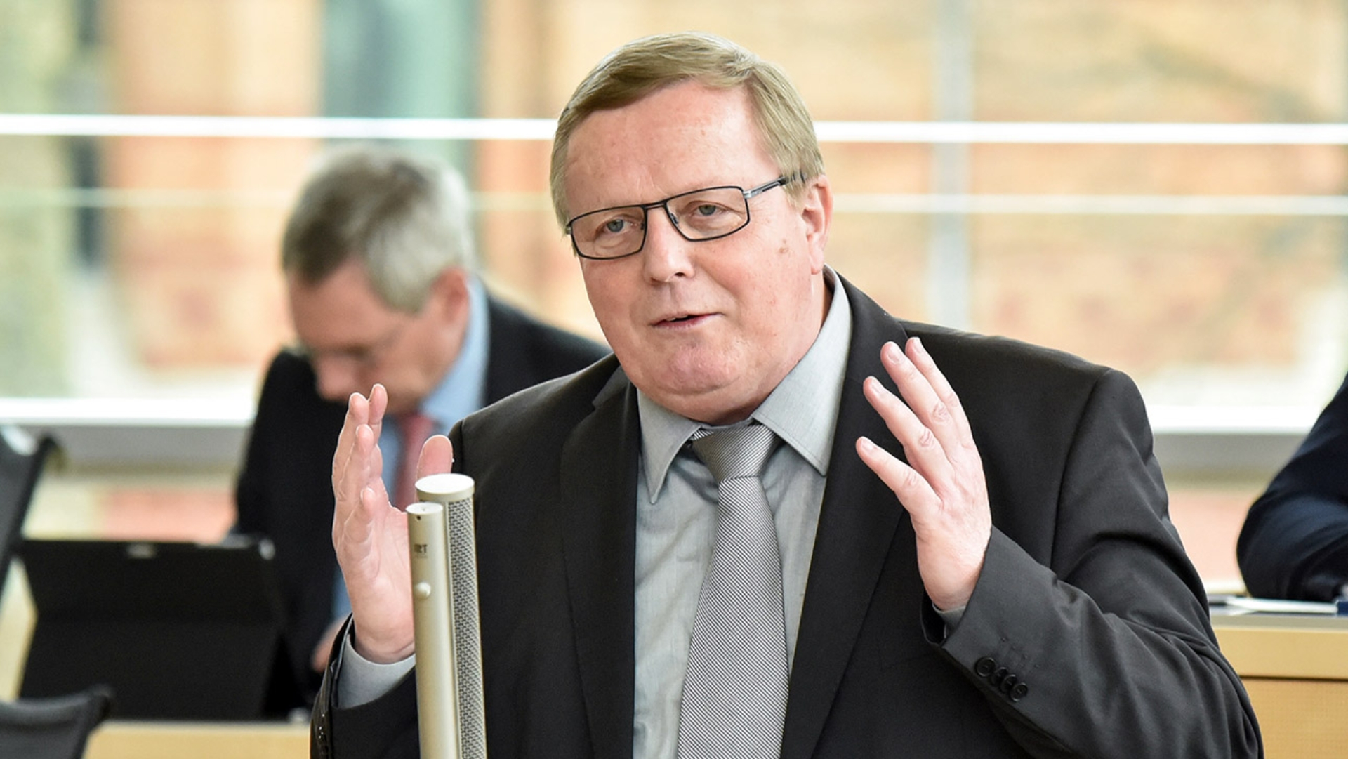 Der CDU-Abgeordnete steht am Mikrofon im Plenarsaal des Landtages und hält mit ausgebreiteten Armen eine Rede.