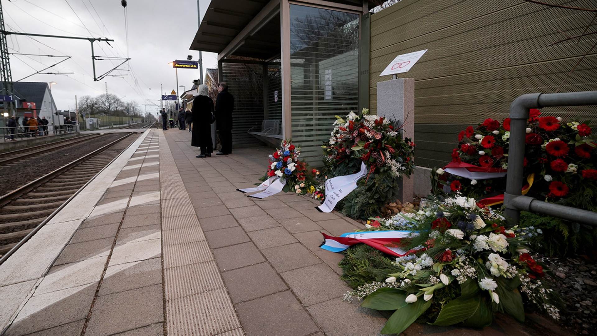 Blumengestecke und Kränze liegen am Gedenkstein auf dem Bahnsteig für die Opfer der Messerattacke im Regionalzug in Brokstedt. 