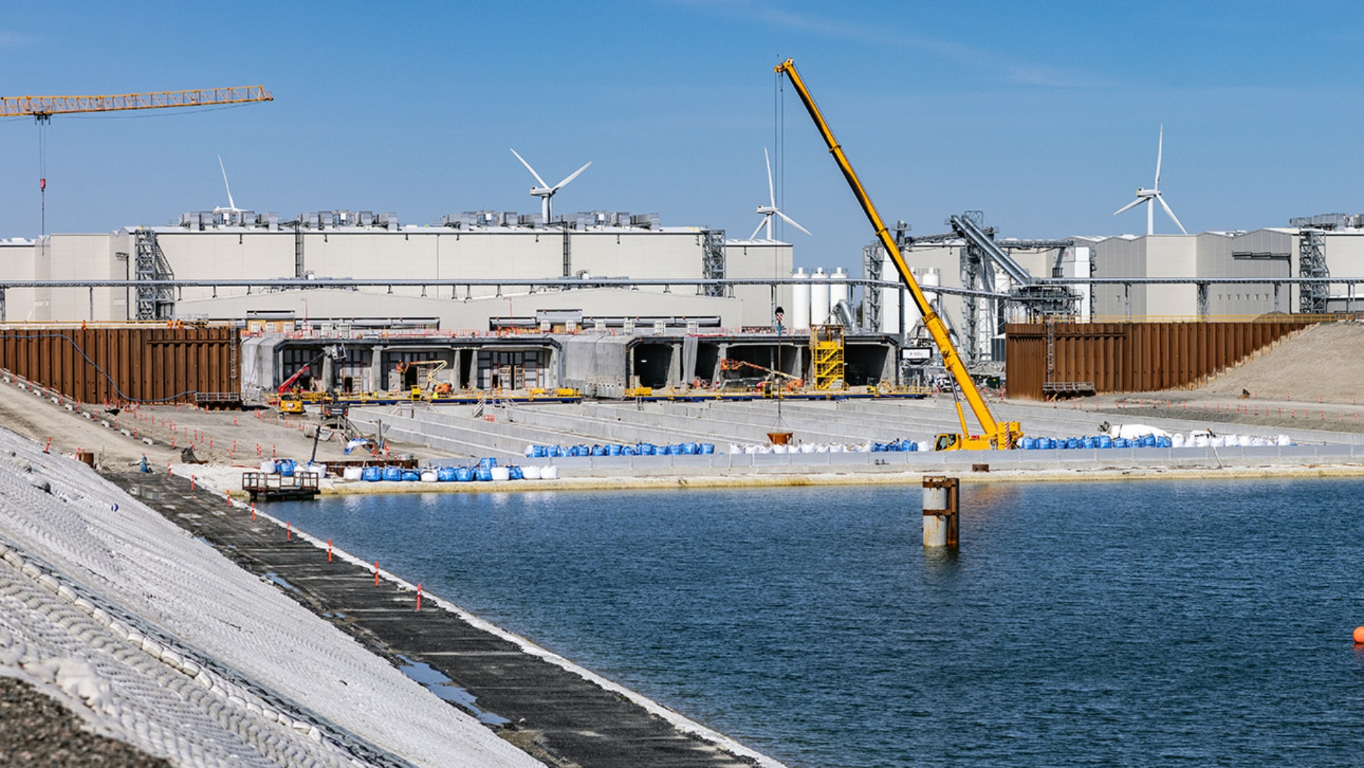 Techniker arbeiten mit einem Hebekran auf der Baustelle des Fehmarnbelt-Tunnels