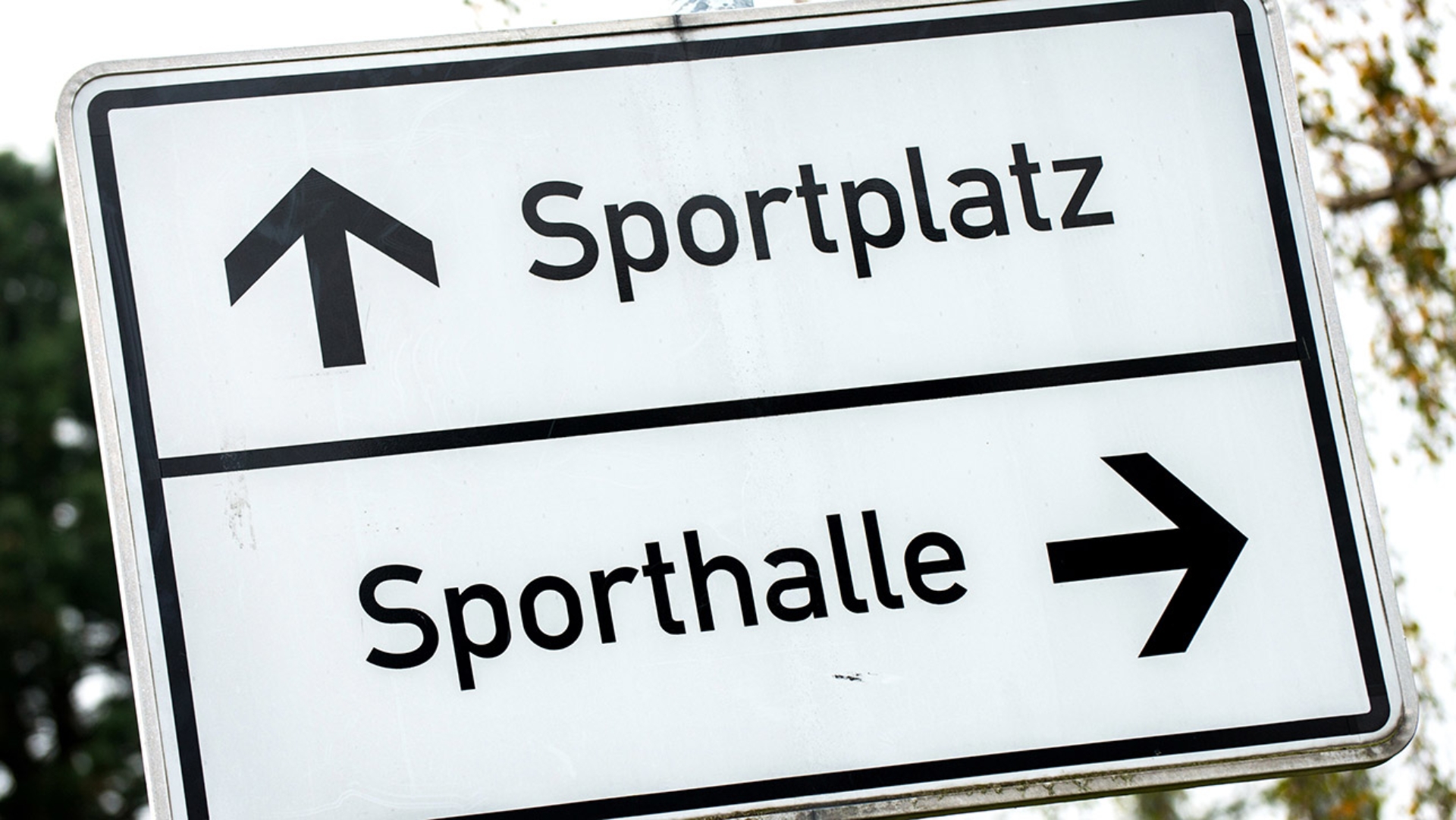 Ein Schild weist den Weg zu Sportplatz und Sporthalle.