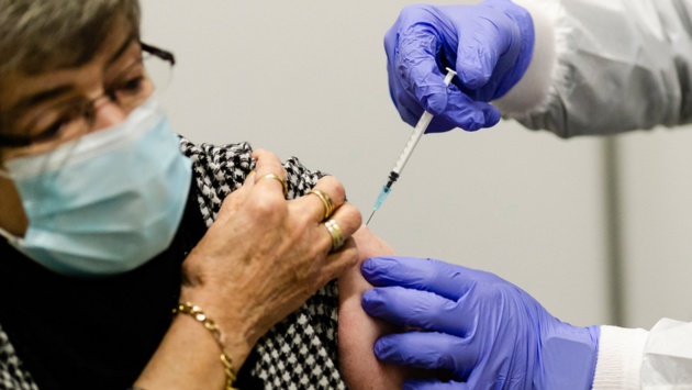 In den Arm einer Frau wird die Impfung gegen das Coronavirus injiziert.