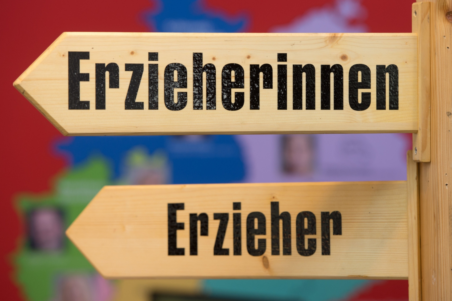 Blick auf zwei Schilder mit Pfeilen. Auf einem steht "Erzieherin", auf dem anderen "Erzieher".