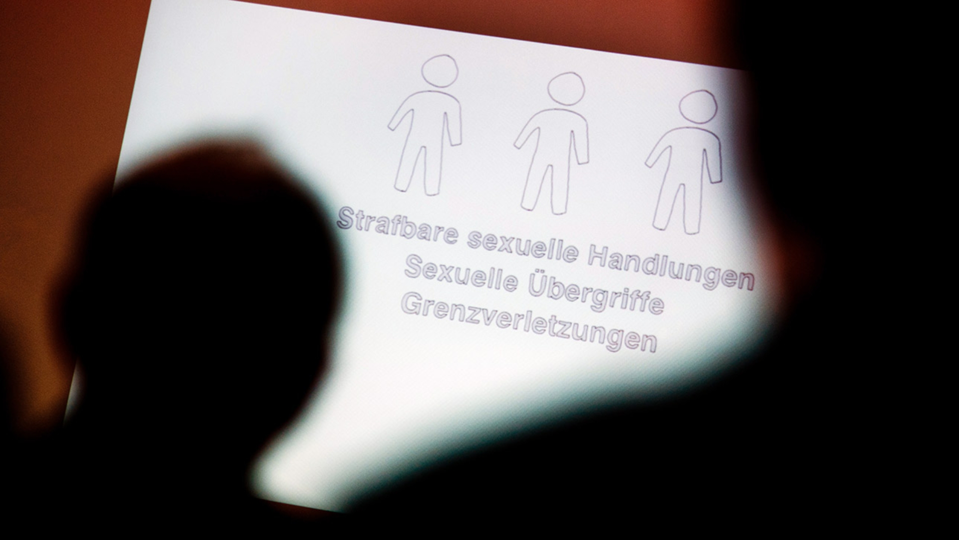Tagungsteilnehmer betrachten bei einer Fachtagung zur Prävention von sexuellem Missbrauch eine Präsentation.