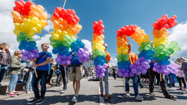 Menschen mit bunten Luftballons, die das Wort „Pride“ bilden.