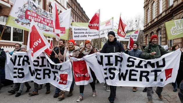 Beschäftigte des Öffentlichen Dienstes demonstrieren mit Transparenten mit der Aufschrift "Wir sind es wert" während eines Warnstreiks vor dem Gewerkschaftshaus in Kiel für höhere Gehälter.