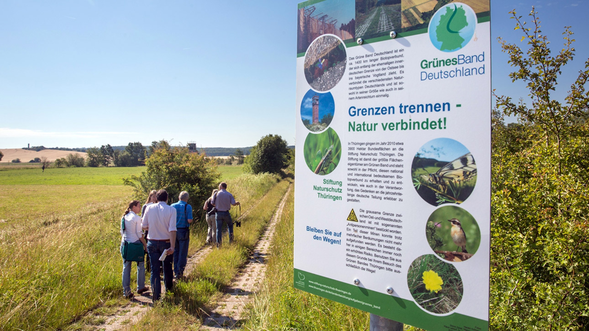 Spaziergänger laufen auf einem ehemaligen Kolonnenweg im Naturschutzgebiet Grünes Band.