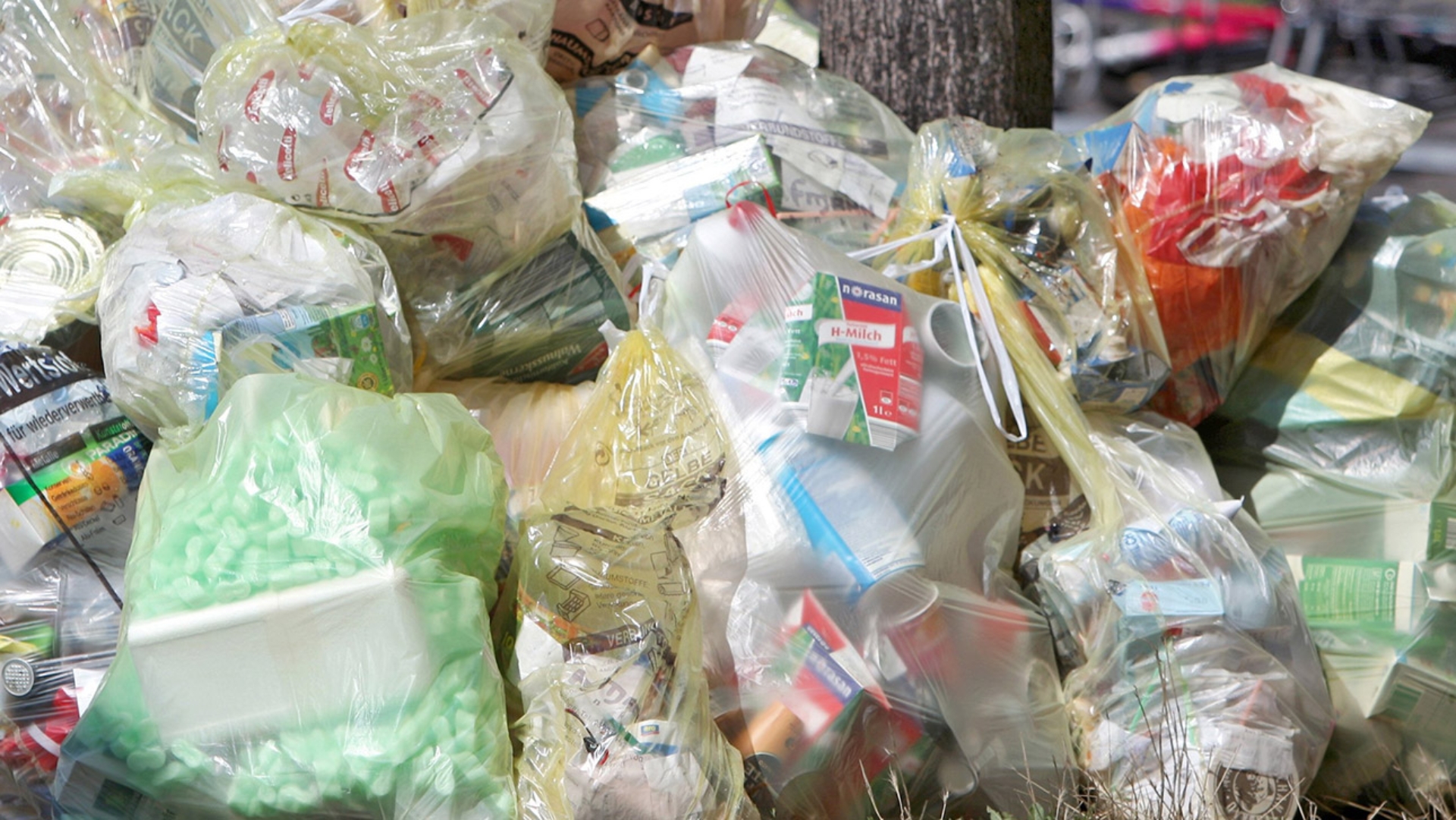 Zahlreiche Gelbe Säcke liegen auf dem Gehweg auf einem Haufen für die Abholung bereit.