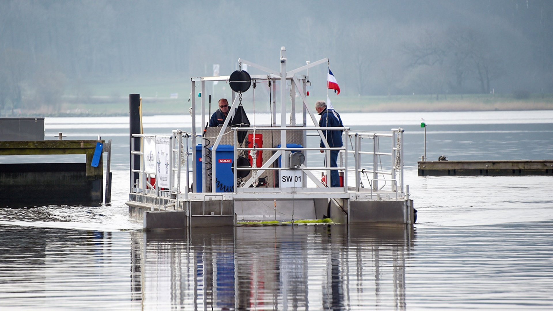 Ein Schiff mit einer Siebvorrichtung zur Reinigung der Schlei von Plastikpartikeln fährt vor dem Stadthafen von Schleswig auf der Schlei, einem Meeresarm der Ostsee.